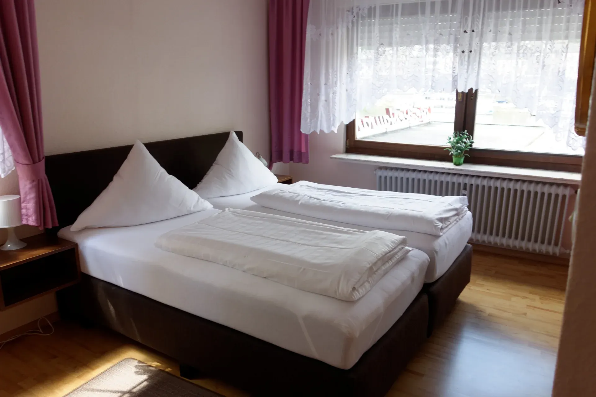 Furnished double room with a light-coloured bed and balcony access
