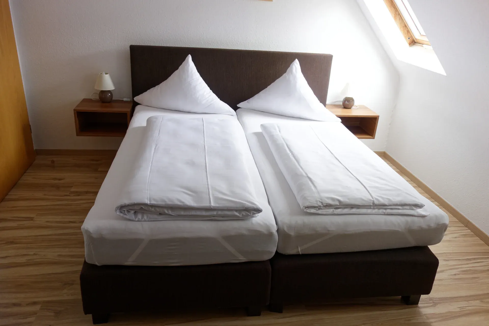 Double room with light bed linen and wooden furniture